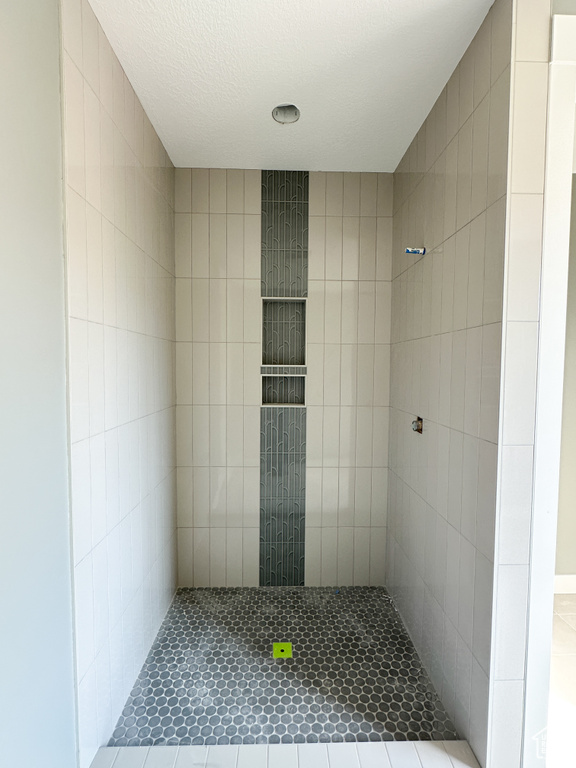 Bathroom featuring a tile shower and a textured ceiling