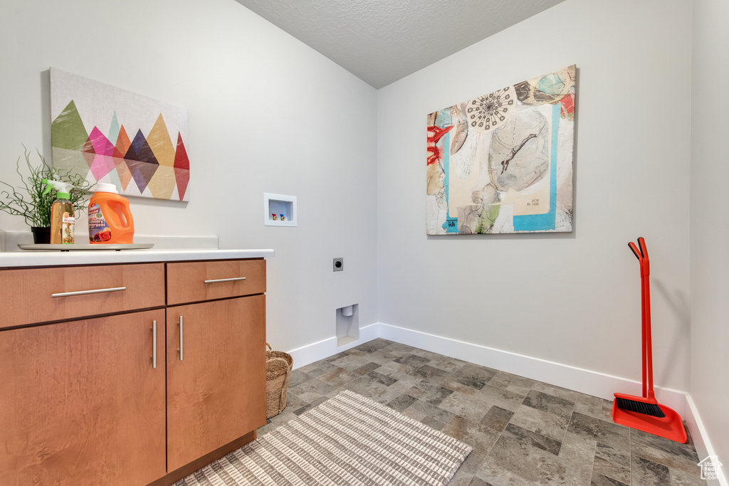 Laundry room featuring hookup for a washing machine, cabinets, hookup for an electric dryer, and a textured ceiling