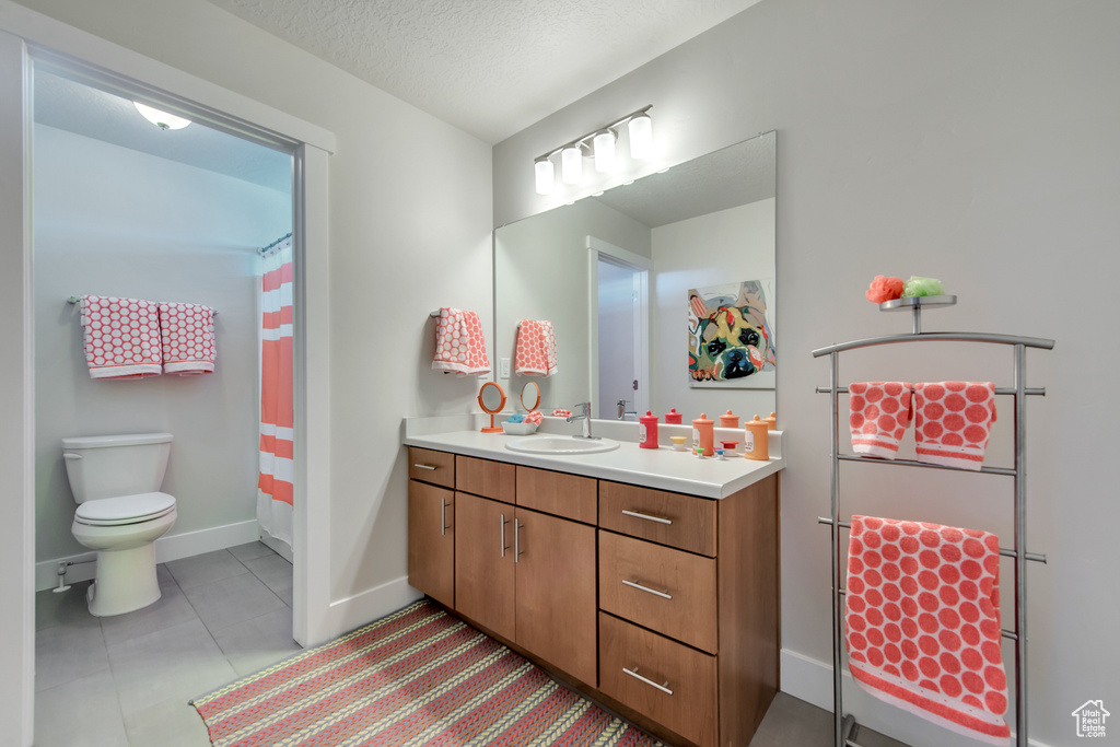 Bathroom featuring vanity, toilet, a textured ceiling, a shower with curtain, and tile patterned flooring