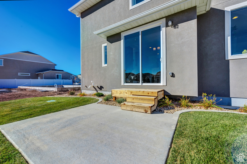 Property entrance with a patio and a lawn