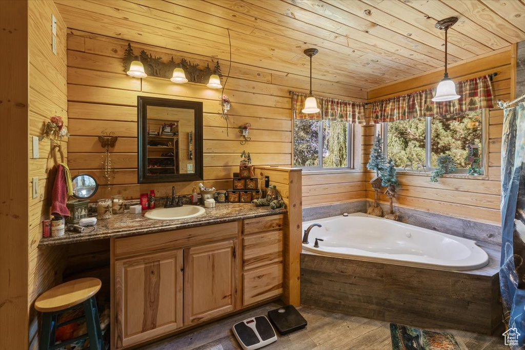 Bathroom featuring vanity, wood walls, a tub, wooden ceiling, and hardwood / wood-style floors