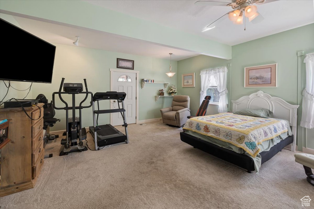 Carpeted bedroom featuring ceiling fan and beamed ceiling