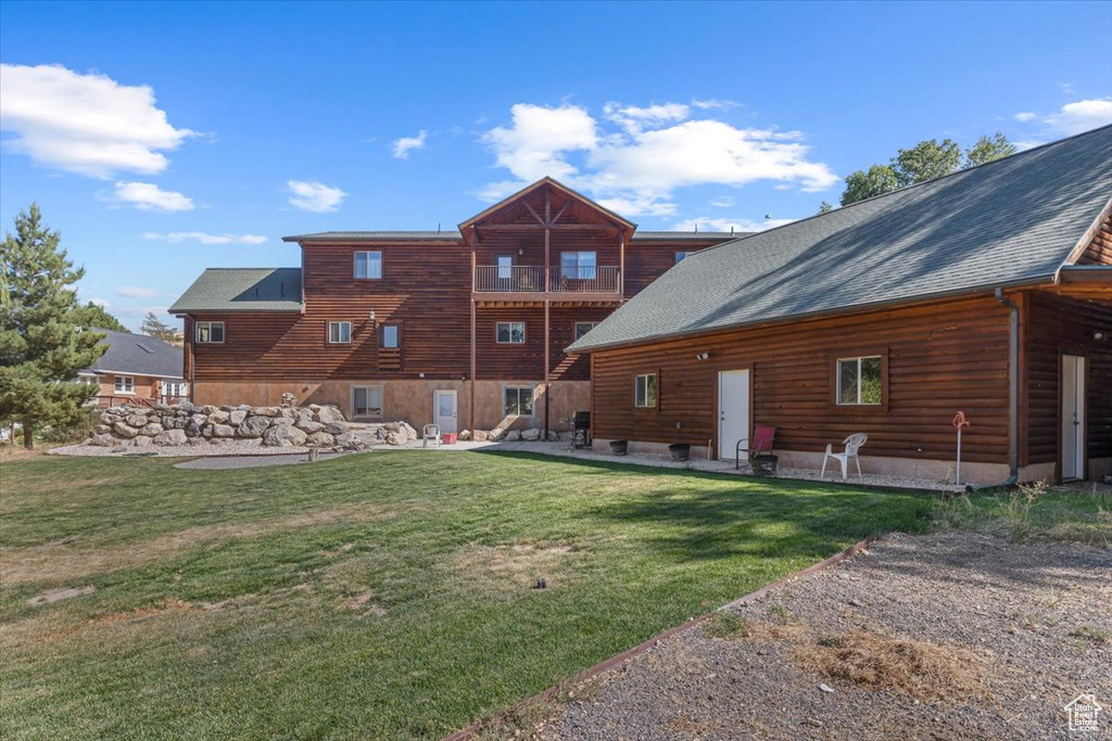 Back of property with a balcony and a lawn