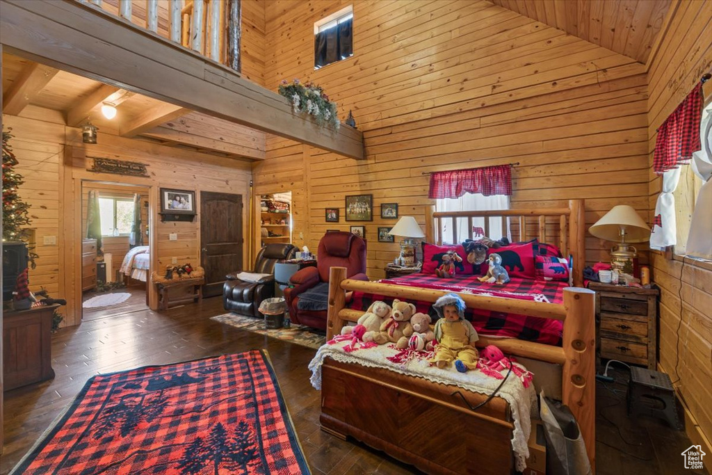 Bedroom with high vaulted ceiling, wooden walls, and dark wood-type flooring