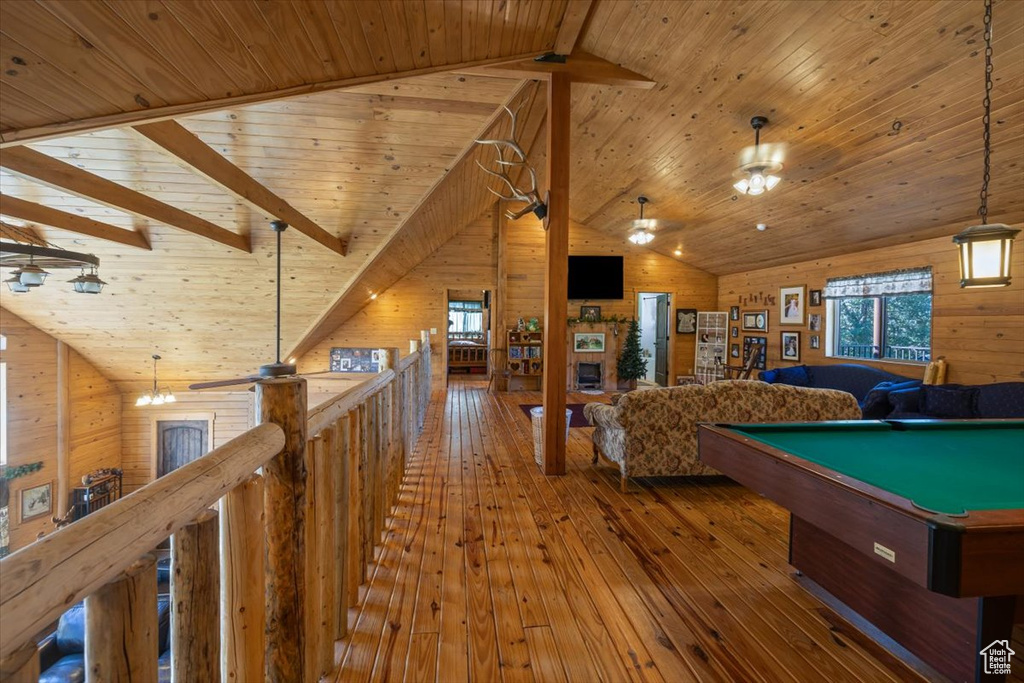 Game room with wood walls, wood ceiling, lofted ceiling with beams, and hardwood / wood-style flooring