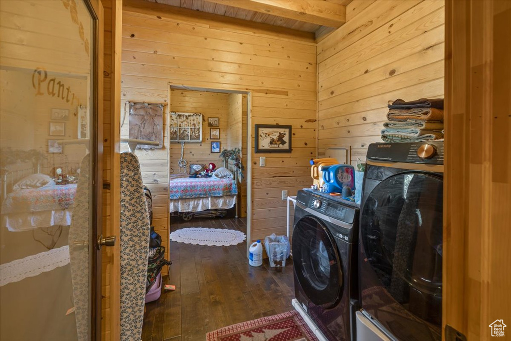 Laundry area with separate washer and dryer, dark hardwood / wood-style floors, and wood walls