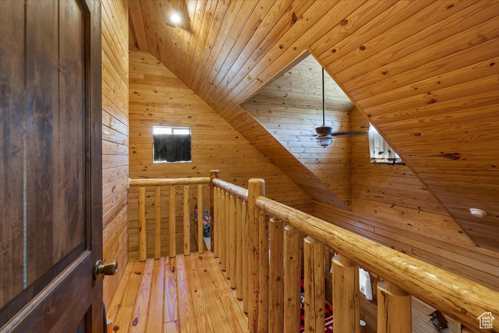 Corridor featuring wood walls, light hardwood / wood-style floors, wood ceiling, and lofted ceiling