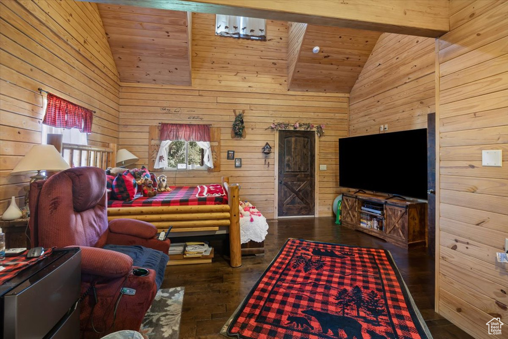 Bedroom with high vaulted ceiling, beam ceiling, wood walls, and dark hardwood / wood-style flooring