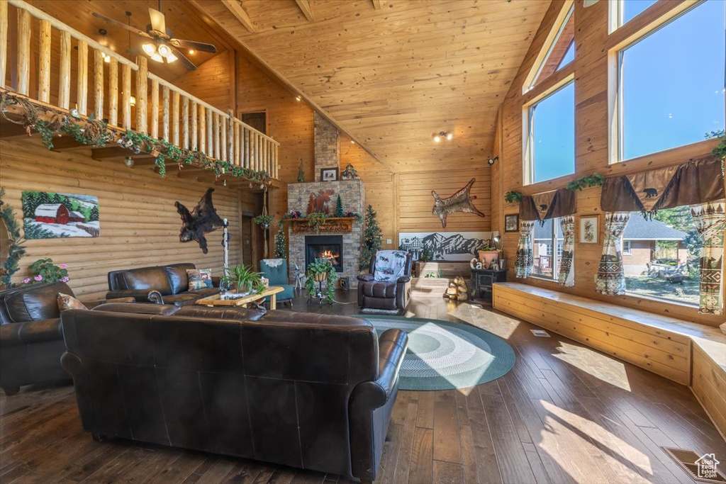 Living room with a stone fireplace, wood ceiling, dark hardwood / wood-style flooring, and high vaulted ceiling