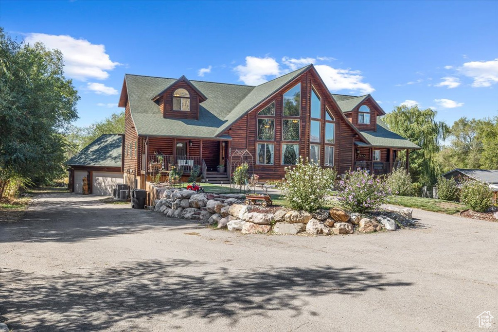 Log-style house with central air condition unit, a garage, and a porch