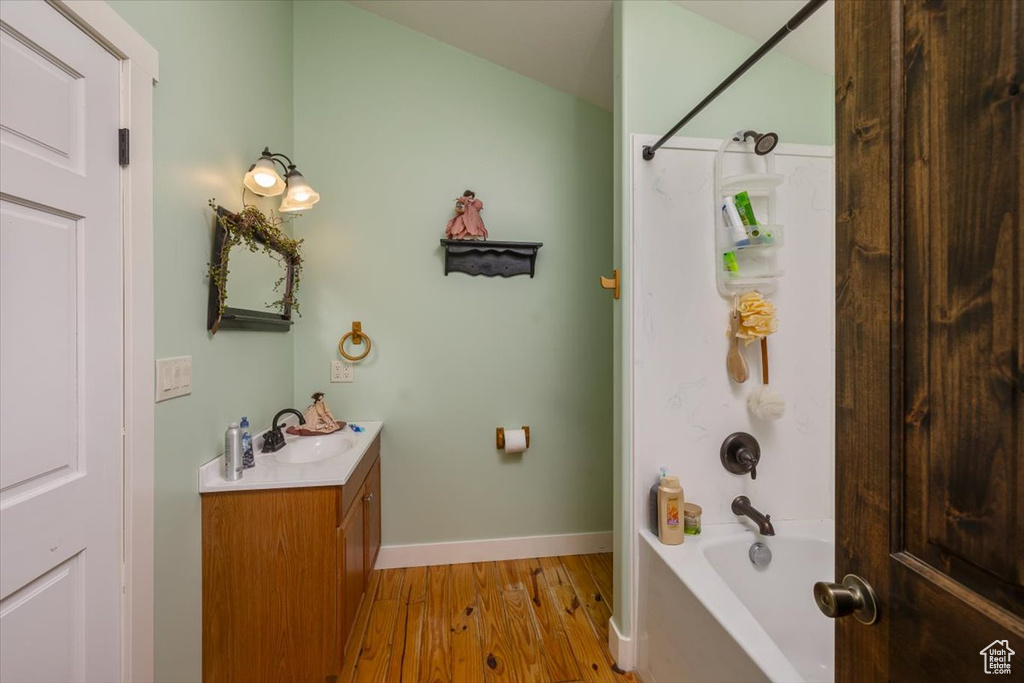 Bathroom with washtub / shower combination, wood-type flooring, and vanity