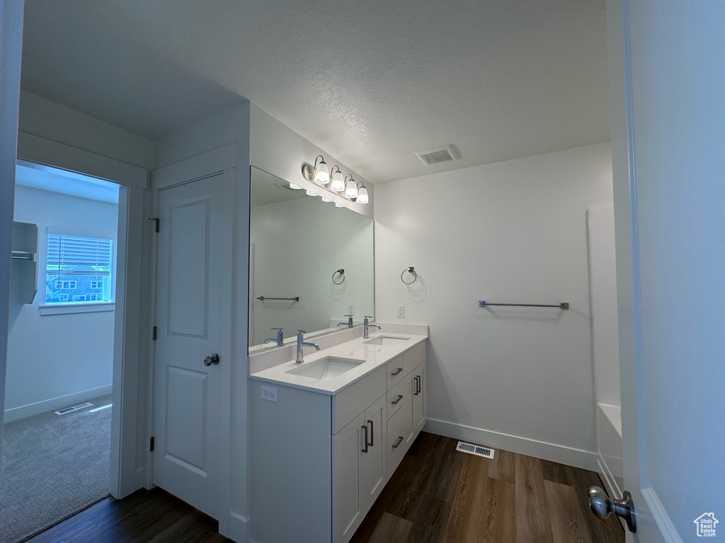 Bathroom featuring hardwood / wood-style flooring, a tub to relax in, vanity, and a textured ceiling