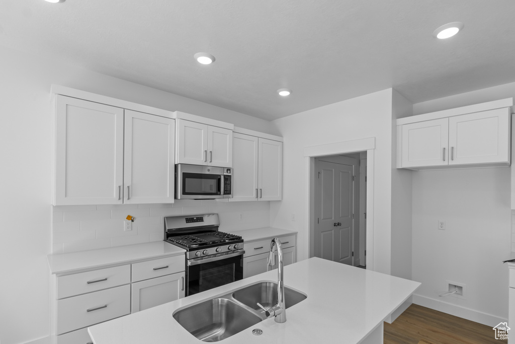 Kitchen with tasteful backsplash, sink, dark hardwood / wood-style flooring, white cabinetry, and appliances with stainless steel finishes