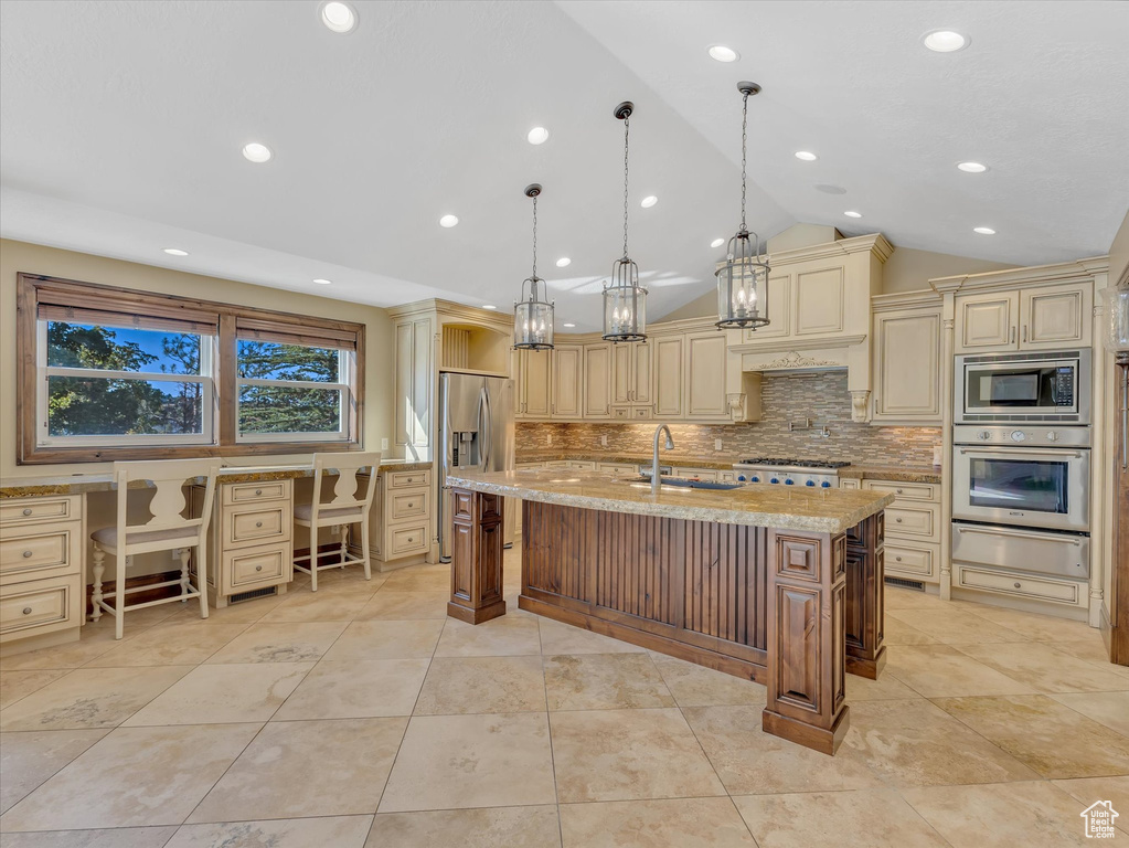 Kitchen featuring a center island with sink, decorative light fixtures, vaulted ceiling, sink, and built in desk