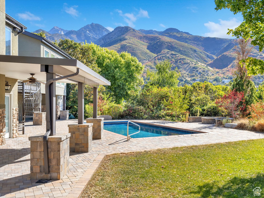 View of swimming pool featuring a patio, a lawn, a mountain view, and ceiling fan