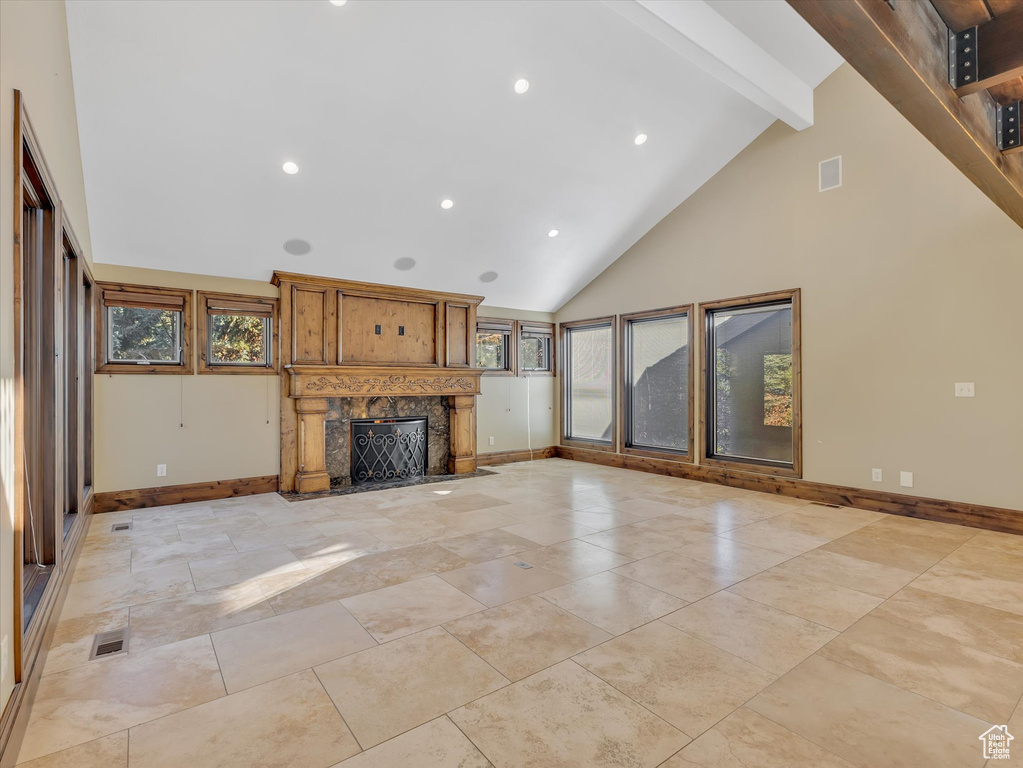 Unfurnished living room featuring a fireplace, high vaulted ceiling, and beamed ceiling