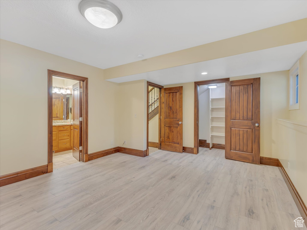 Unfurnished bedroom with a closet, connected bathroom, light hardwood / wood-style floors, and a walk in closet