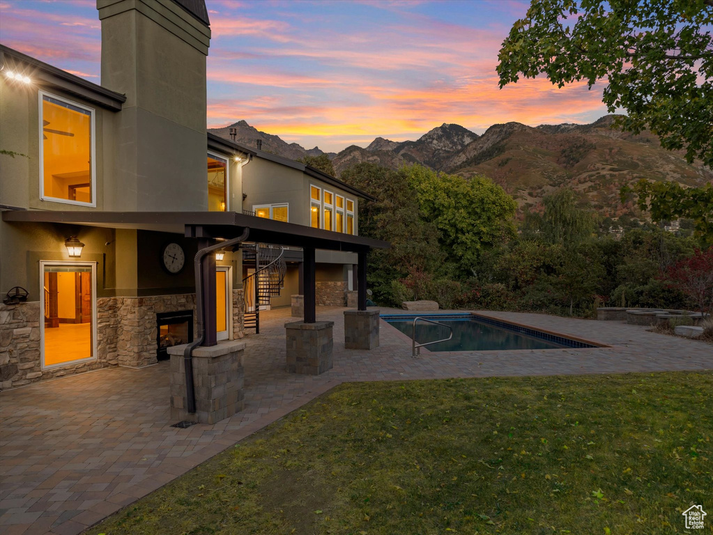 Pool at dusk featuring a yard, a patio area, and a mountain view