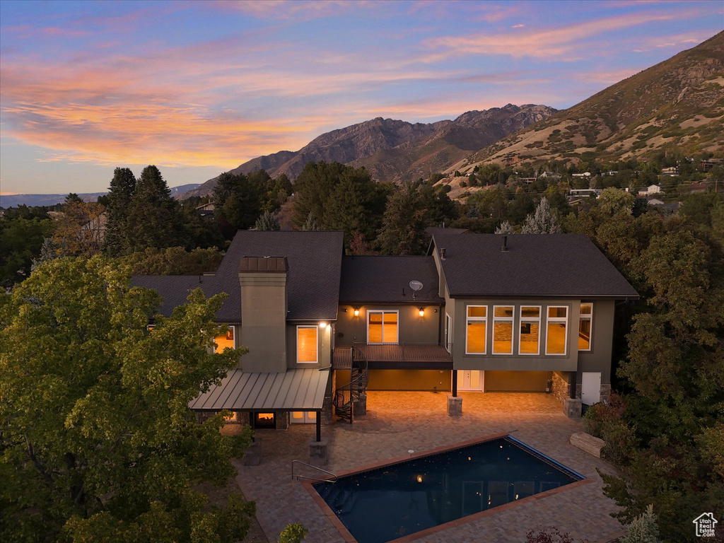 Back house at dusk featuring a mountain view and a patio area