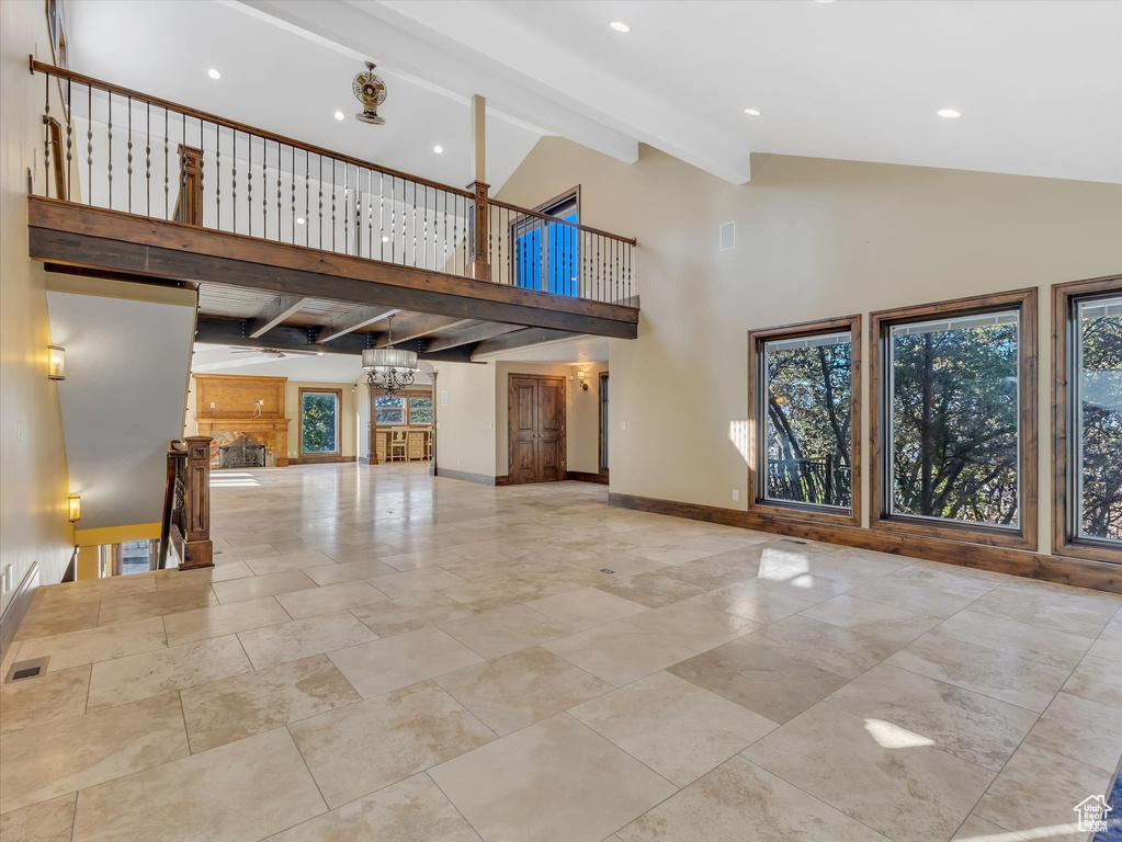 Unfurnished living room featuring a chandelier, beam ceiling, and high vaulted ceiling