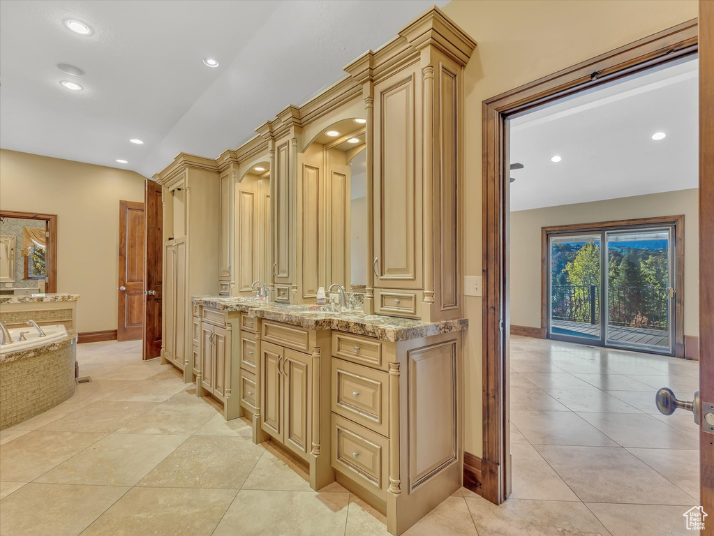 Bathroom with tile patterned floors, decorative columns, a tub, and vanity