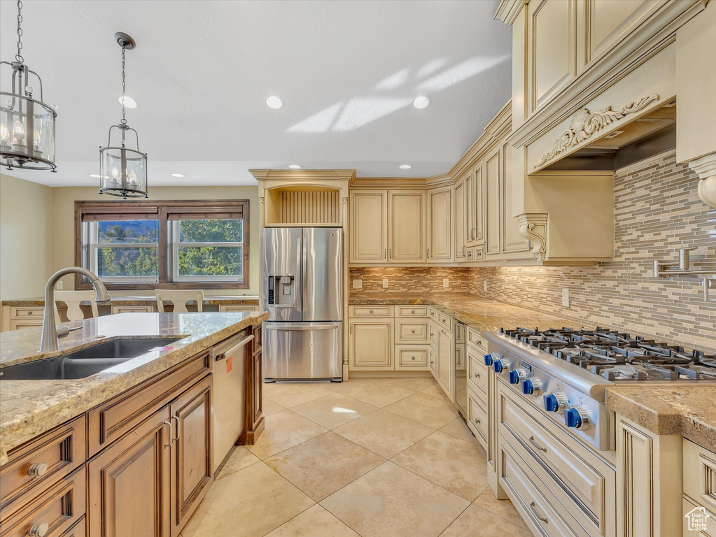 Kitchen featuring decorative backsplash, pendant lighting, sink, stainless steel appliances, and light stone countertops