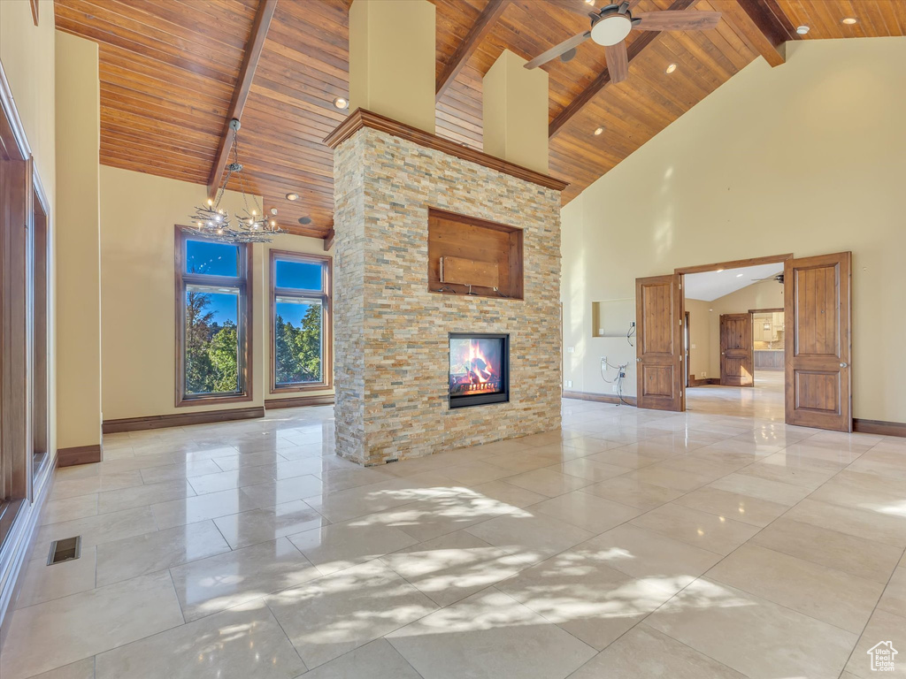 Unfurnished living room featuring high vaulted ceiling, beam ceiling, a stone fireplace, and wooden ceiling