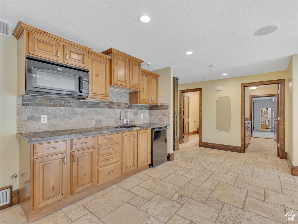 Kitchen with tasteful backsplash, light brown cabinets, black appliances, and sink