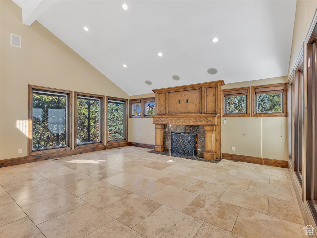 Unfurnished living room with beam ceiling, a high end fireplace, and high vaulted ceiling