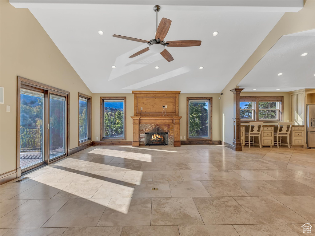 Unfurnished living room with ceiling fan, beam ceiling, a high end fireplace, high vaulted ceiling, and decorative columns