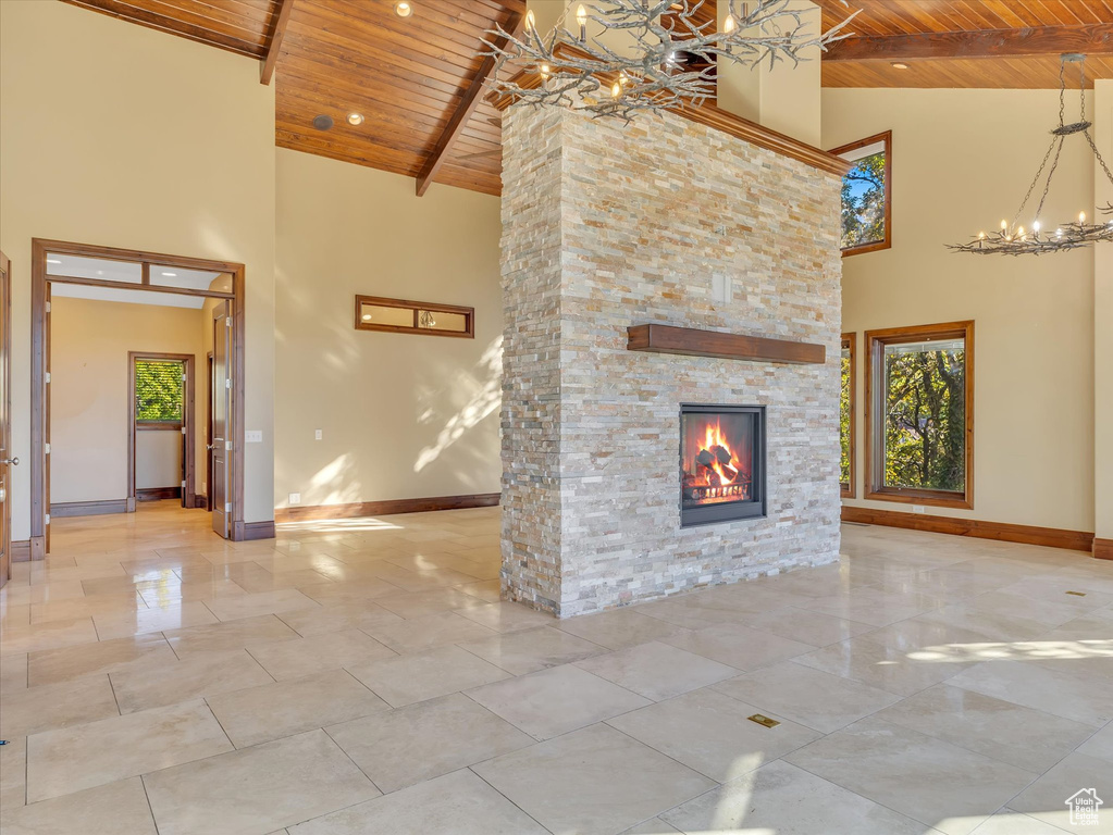 Unfurnished living room featuring beamed ceiling, a chandelier, wooden ceiling, a fireplace, and high vaulted ceiling