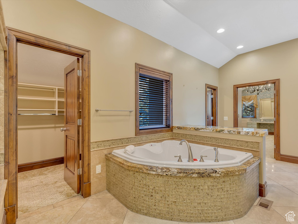 Bathroom with tile patterned flooring, vaulted ceiling, and tiled bath