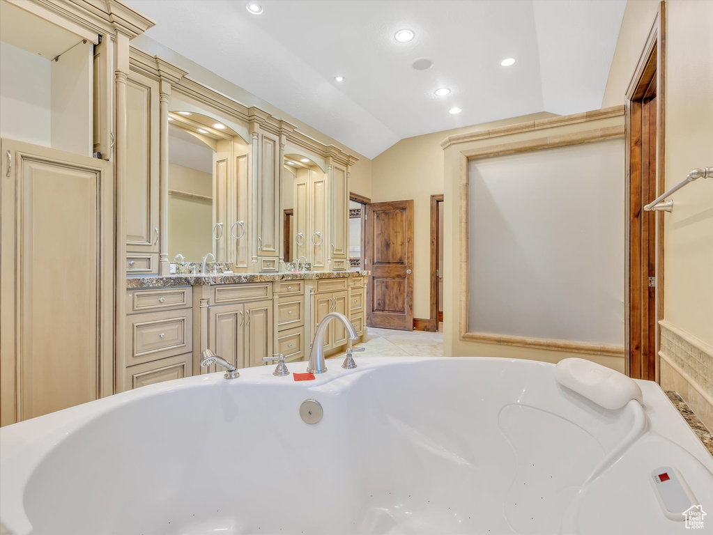 Bathroom featuring vanity, vaulted ceiling, and a washtub