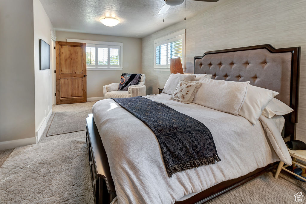 Bedroom featuring light carpet, a textured ceiling, and ceiling fan