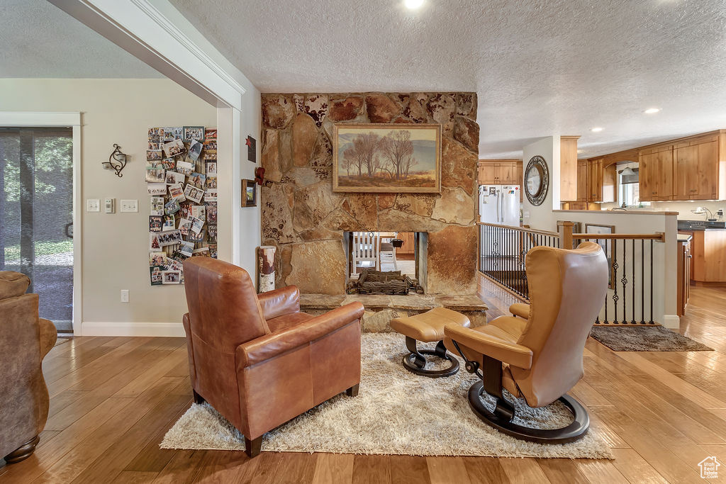 Living room with a fireplace, light hardwood / wood-style flooring, and a textured ceiling