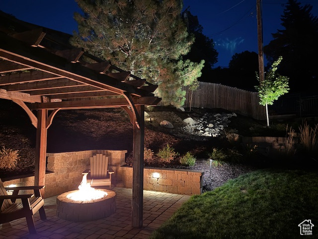 Patio at twilight with a fire pit and a pergola