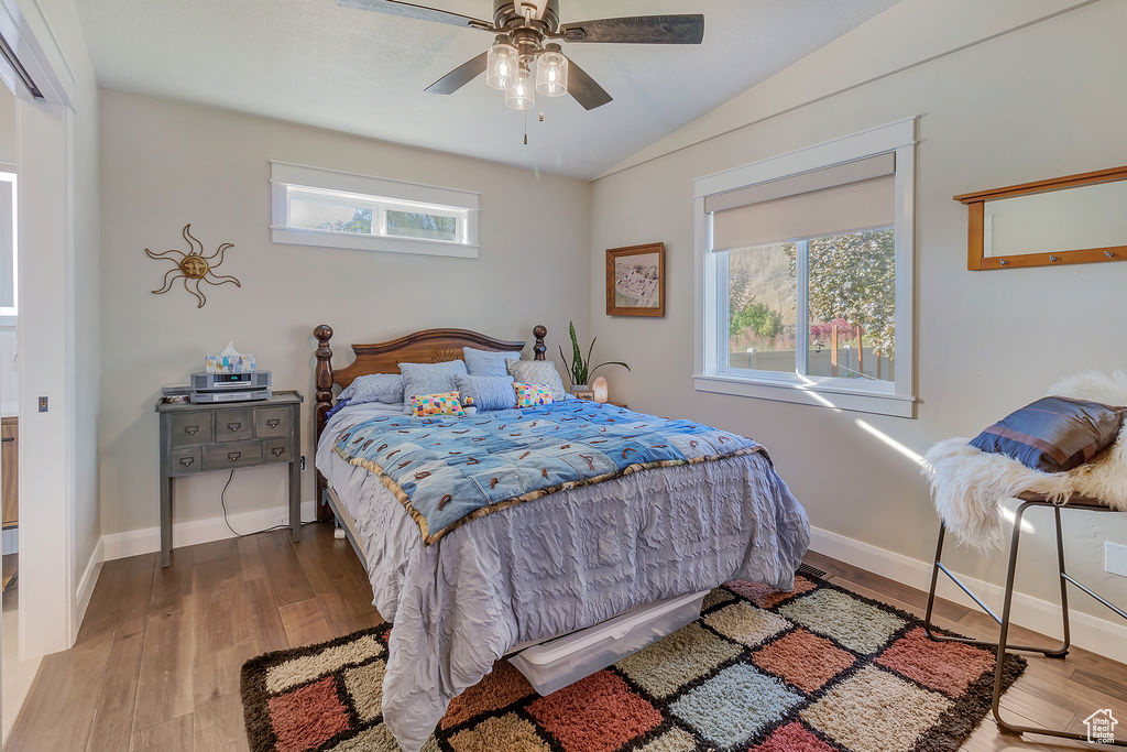 Bedroom featuring vaulted ceiling, multiple windows, ceiling fan, and hardwood / wood-style floors