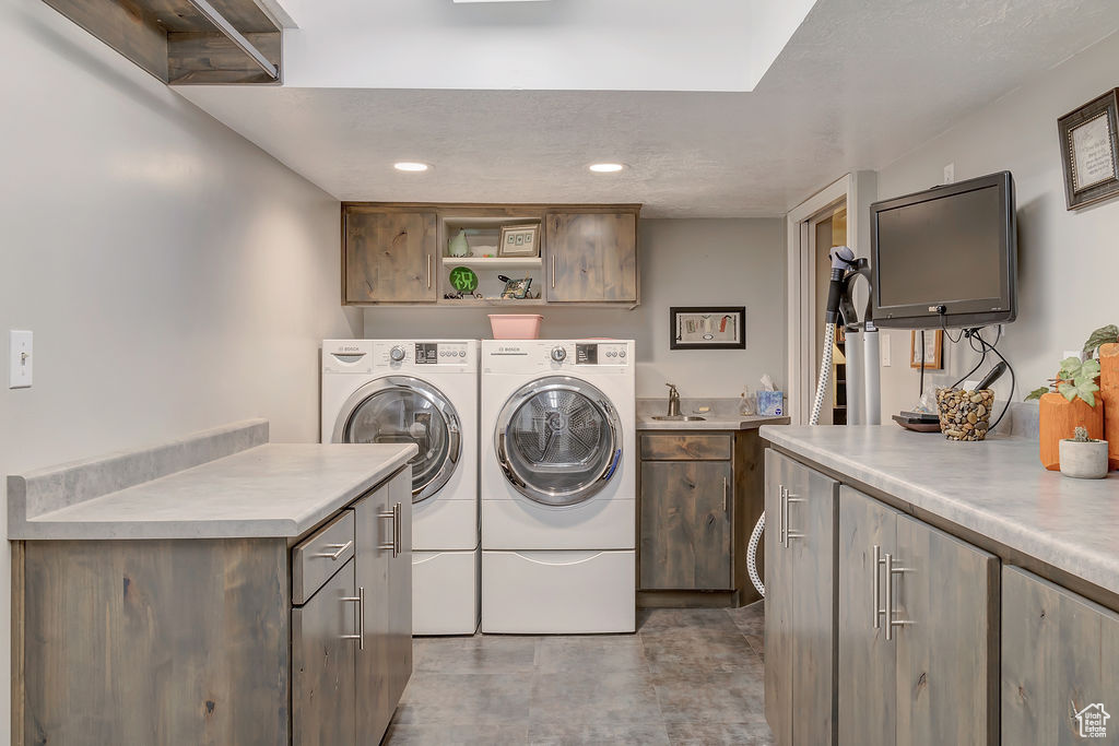 Laundry area with washer and dryer, sink, and cabinets