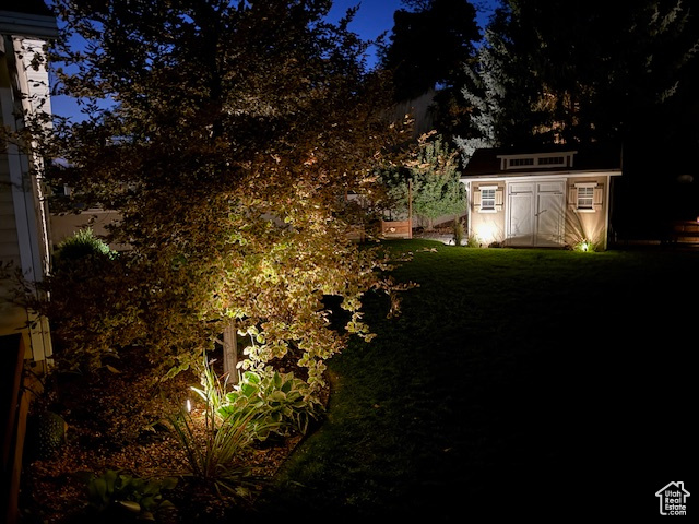 Yard at night featuring a storage unit