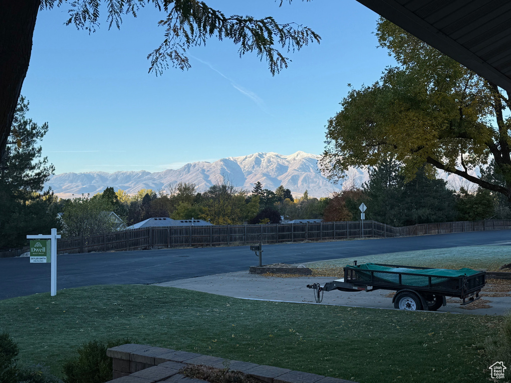 View of tennis court featuring a mountain view and a lawn