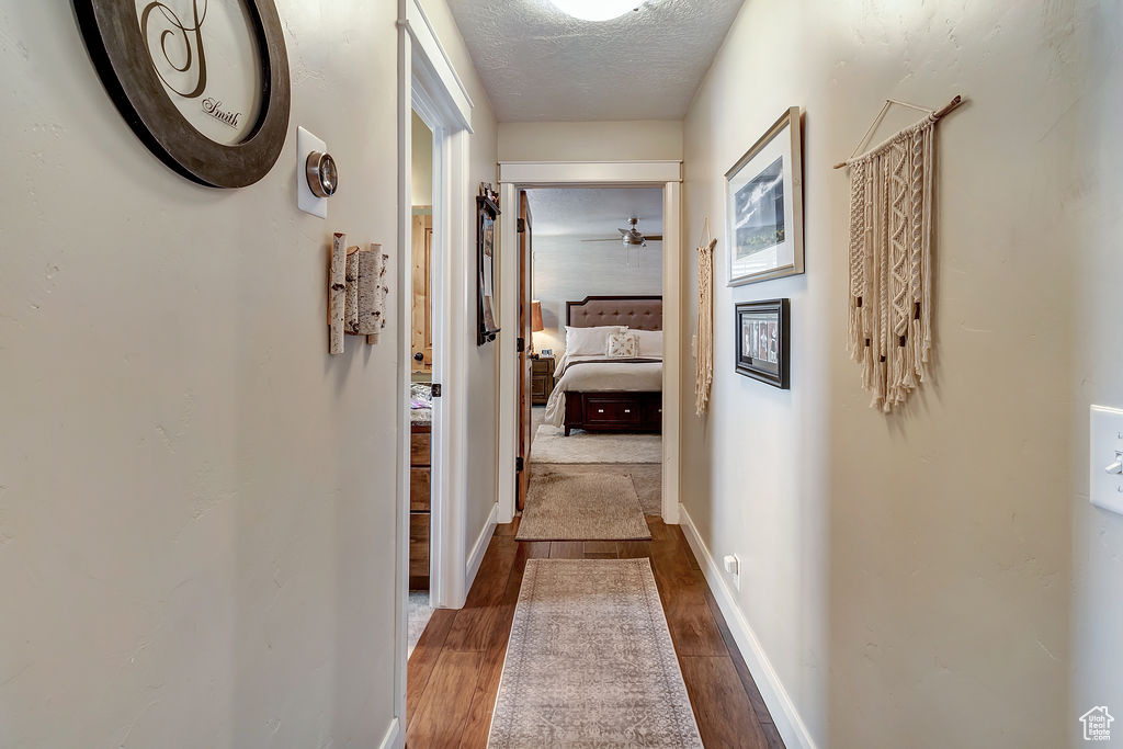 Corridor featuring a textured ceiling and dark hardwood / wood-style flooring