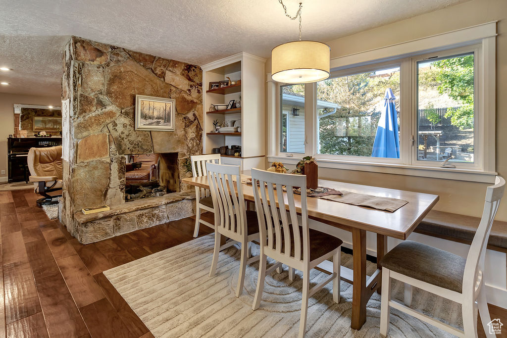 Dining room featuring a textured ceiling, a fireplace, and hardwood / wood-style floors