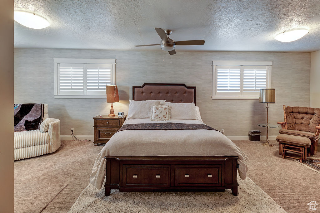 Carpeted bedroom with ceiling fan and a textured ceiling