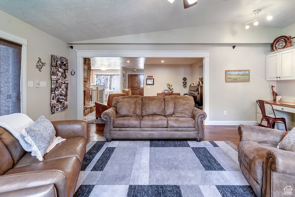 Living room with lofted ceiling, dark hardwood / wood-style flooring, and a textured ceiling