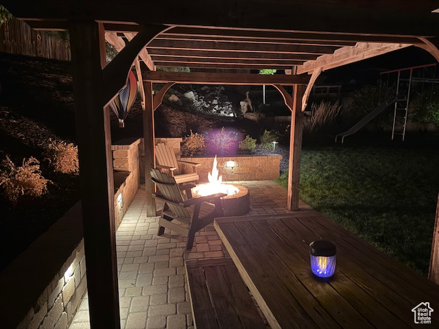 Patio at night with an outdoor fire pit and a pergola