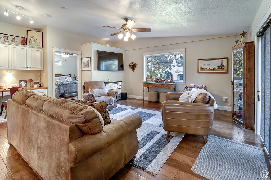 Living room with lofted ceiling, ceiling fan, dark hardwood / wood-style floors, and a textured ceiling