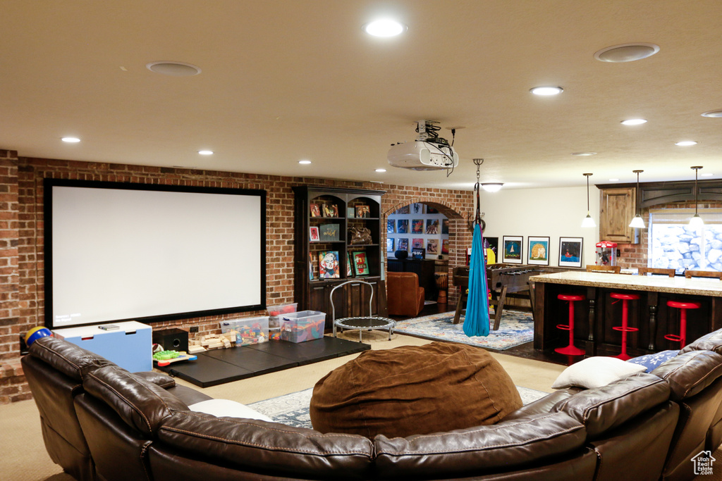 Home theater room featuring brick wall and light colored carpet