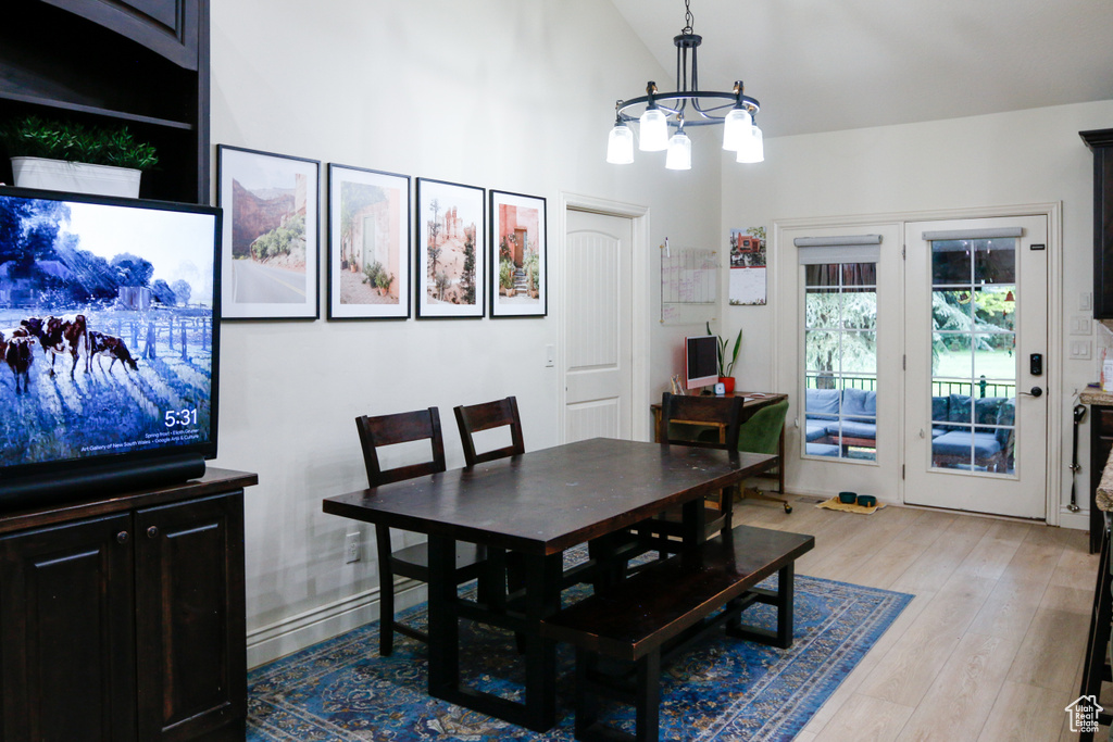 Dining area featuring high vaulted ceiling, french doors, a chandelier, and light hardwood / wood-style flooring