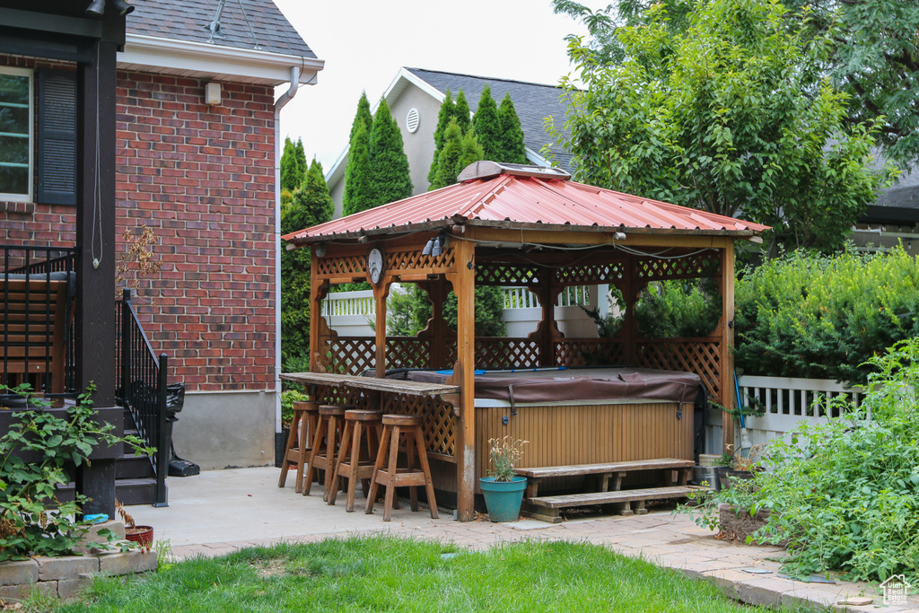 Wooden deck with a gazebo, a patio, and a hot tub