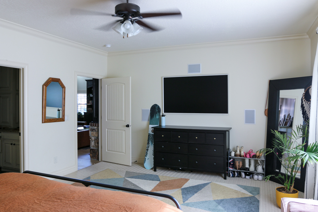 Carpeted bedroom with ceiling fan, ensuite bath, and crown molding